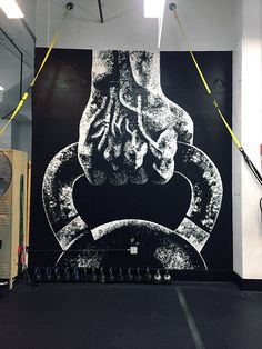 a large black and white painting on the side of a wall in a gym area