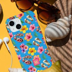 a blue phone case with flowers on it next to headphones, sunglasses and lemons