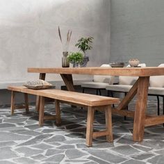 a wooden table and bench in a room with grey tiles on the floor next to a brick wall