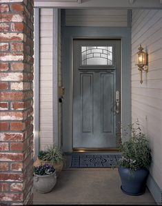 the front door is painted blue and has two planters on either side