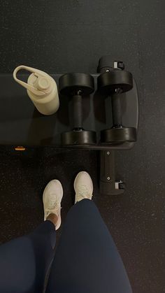 a pair of white shoes sitting on top of a black shelf next to a cup