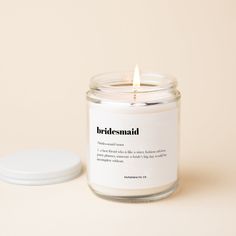 a white candle sitting on top of a table next to a small container with a lid