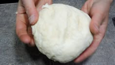 two hands are holding a ball of dough