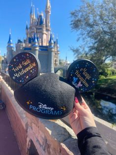 someone is holding up their mouse ears in front of the castle at disney's magic kingdom