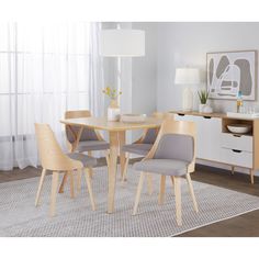 a dining room table with four chairs and a rug on the floor in front of it