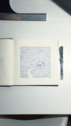 an open book sitting on top of a white table next to a pen and paper