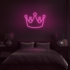 a bed with a neon crown on the wall above it