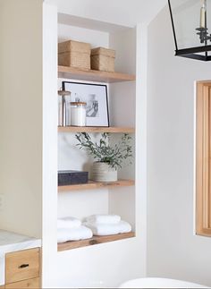 the shelves in this bathroom are made out of wood and have white towels on them