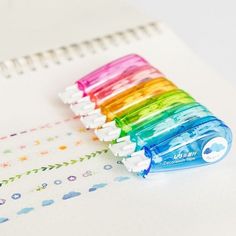 a rainbow colored toothbrush sitting on top of a notebook