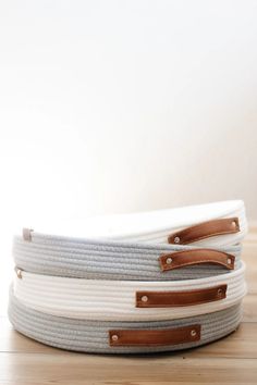 three white and grey baskets sitting on top of a wooden table next to each other