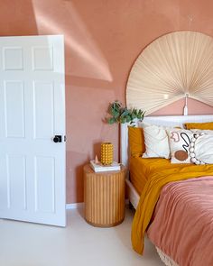 a bedroom with pink walls and orange bedding in the corner, along with a round mirror on the wall