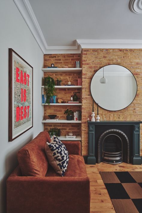 Victorian modern living room with exposed brick wall and checkerboard rug. Exposed brick wall and retro design for a young professional home. Brick Sofa Living Room, Exposed Brick Feature Wall Living Room, Interior Brick Wall Ideas Living Room, Exposed Brick Color Palette, Brickwall Interiors Living Room, Exposed Brick Fireplace Living Room, Red Brick Wall Living Room, Brick Feature Wall Living Room, Victorian Modern Living Room