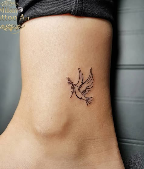 Pretty Dove Ankle Tattoo Idea Bird Tatoos Woman Wrist, Small Dove Tattoo Design For Women, Dove With Olive Branch Tattoo Simple, Dainty Dove Tattoo, Dainty Catholic Tattoos, Dove Flying Tattoo, Angel Tattoo Placement, Cross With Birds Tattoo, Dove Hand Tattoo