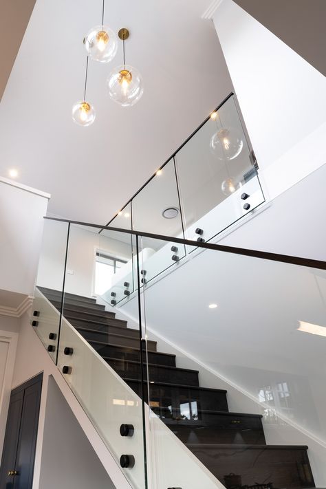 Experience the elegance of matte black sleek stairs with a transparent glass railing. Against a backdrop of pristine white walls, these stairs become the standout feature, blending modern design with a clean and sophisticated aesthetic. Discover the perfect fusion of style and simplicity in this stunning architectural detail. #SleekStairs #MatteBlack #GlassRailing #ModernDesign #CleanAesthetic Black Stairs With Glass Railing, Glass Stair Case Railing, Staircase Glass Railing Design, Glass Staircase Railing, Rock Pigeon, Montgomery Homes, Glass Railing Stairs, Black Staircase, Glass Handrail