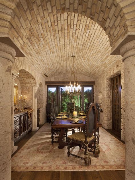 With its brick barrel ceiling and rough stone walls, this dining room could double as a wine cellar. Heavy, hand-carved dining chairs surround a wood dining table under the glow of a filigreed chandelier. Tuscan Dining Room, Tuscan Dining Rooms, Tuscan Style Decor, Style Toscan, Italian Style Home, Rustic Italian Home, Stone Walls Interior, Tuscan Style Homes, Stone Interior