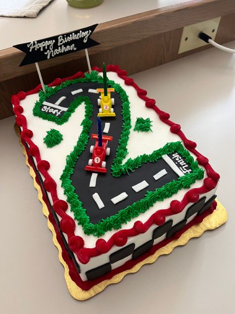 Sheet cake with a large number 2 designed like a race track with two race cars. Checkered border made of fondant, green grass made of buttercream.  Also has a banner that reads Happy Birthday, Nathan. 2 Race Car Cake, Lightening Mcqueen Sheet Cake, Two Fast Race Car Birthday Cake, Racetrack Birthday Cake, Two Fast Racing Birthday Party, Two Fast Sheet Cake, Race Car 2nd Birthday Cake, Smash Cake Race Car Theme, 2nd Birthday Car Cake