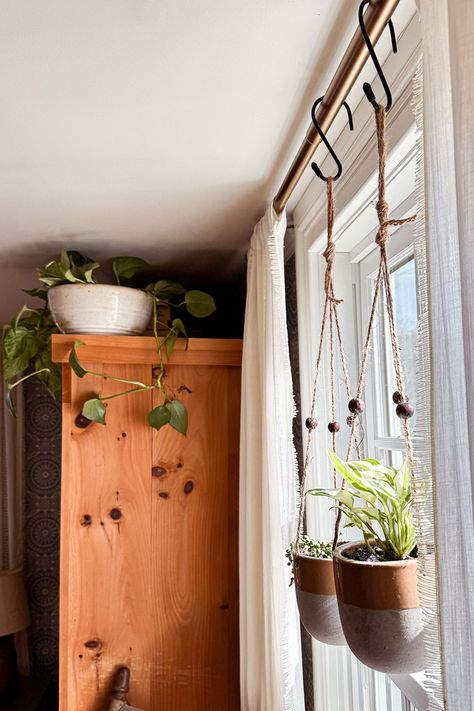 One of the easiest ways to update your bedroom decor is to add bedroom plants. Don't underestimate the power of plants!  Hanging plants from curtain rods is a fun way to add a touch of greenery and update your bedroom decor. Two of my favorite hanging plant varieties include pothos or string of pearls for a unique look. Check out our blog for more tips on updating your bedroom decor with plants. Your oasis awaits! Double Hanging Planter, Hanging Plant In Living Room, Plants Hanging From Curtain Rod, Hanging Plants Over Window, Hanging Plants In Kitchen Ideas, Curtain Rod Plant Hanger Window, Inside Hanging Plants Ideas, Plants Hanging In Front Of Window, Hanging Plant Indoor Ideas