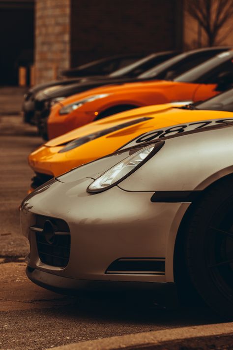 Line up at a car meet in downtown Indianapolis. A grey Porche, then a yellow and orange car, with two black cars in the background. Multiple Cars Photography, Car Style Photography, Cars Lined Up, Two Cars Photography, Classic Car Pictures, Sport Car Photography, Sport Car Photoshoot, Car Photography Composition, Cool Car Photoshoot