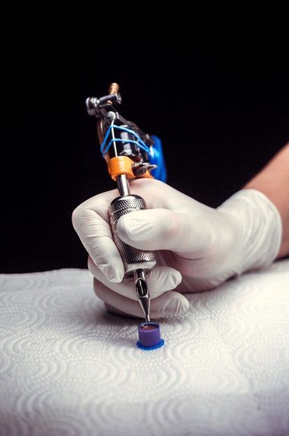 Premium Photo | Hand of a tattoo master with a tattoo gun. hand of a tattoo specialist and a tattoo gun.|#tattoo #handtattoo #tattoos #tattooartist 1106 Hand Holding Tattoo Machine, Tattoo Artist Photography, Hand Holding Tattoo, Background Tattoo, Tattoo Poster, Tattoo Posters, Tattoo Techniques, Tattoo Background, Tattoo Master