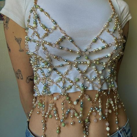 new proj! dm to chat about customs 🩵 perfect for summer over a lil t-shirt or tank top, fun little festival top as pieces move while you dance and just sexc period what can i sayyyyyyy entirely made with gold eyepins + jump rings, variety of pearl beads, gold beads, and natural stone beads, along with gold chain & gold clasps! this was entirely an unplanned project but i’m ecstatic with how it turned out. procrastinating studying for a couple days got me to make this so really procrastinat... Clothes With Pearls, Bead Embroidery Tank Top, Diy Bejeweled Top, Beaded Harness Diy, Beaded Tank Top, Chain Top Outfit, Beaded Top Diy, Custom Diy Ideas, Bead Projects Ideas