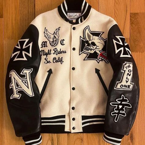 This varsity jacket is a striking blend of vintage and edgy styles, featuring a cream-colored wool body and black leather sleeves. The design is highlighted by bold embroidered patches, including a skull with a horn, "Night Riders So. Calif," and various symbols like the Iron Cross and a Japanese kanji for "happiness." The black and white striped ribbed cuffs, collar, and hem add a classic touch to this statement piece, making it a must-have for anyone looking to stand out. #VarsityJacket #... Letterman Jacket Ideas, Iron Cross, Varsity Jackets, Japanese Kanji, Leather Sleeves, Custom Jacket, Letterman Jacket, Streetwear Men Outfits, Leather Sleeve