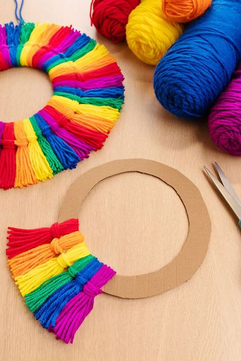 Make a rainbow tassel wreath using colourful yarn and a piece of cardboard! This rainbow craft is SO EASY to make, perfect for kids of all ages and adults. This homemade decor looks so beautiful on display, and you can make it using simple craft supplies. Cardboard Wreath Form, Tassel Wreath, Pride Crafts, Door Toran, Yarn Crafts For Kids, Easy Yarn Crafts, Rainbow Craft, Make A Rainbow, Rainbow Wreath