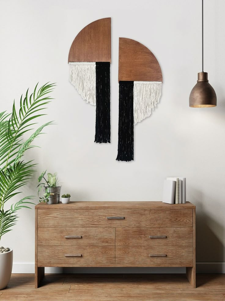 a white wall with two circular mirrors hanging on it's side and a plant in the corner