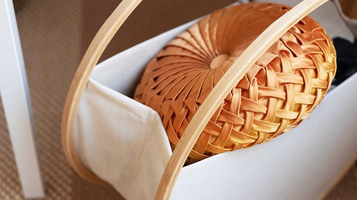 a woven basket with a wooden handle on the floor