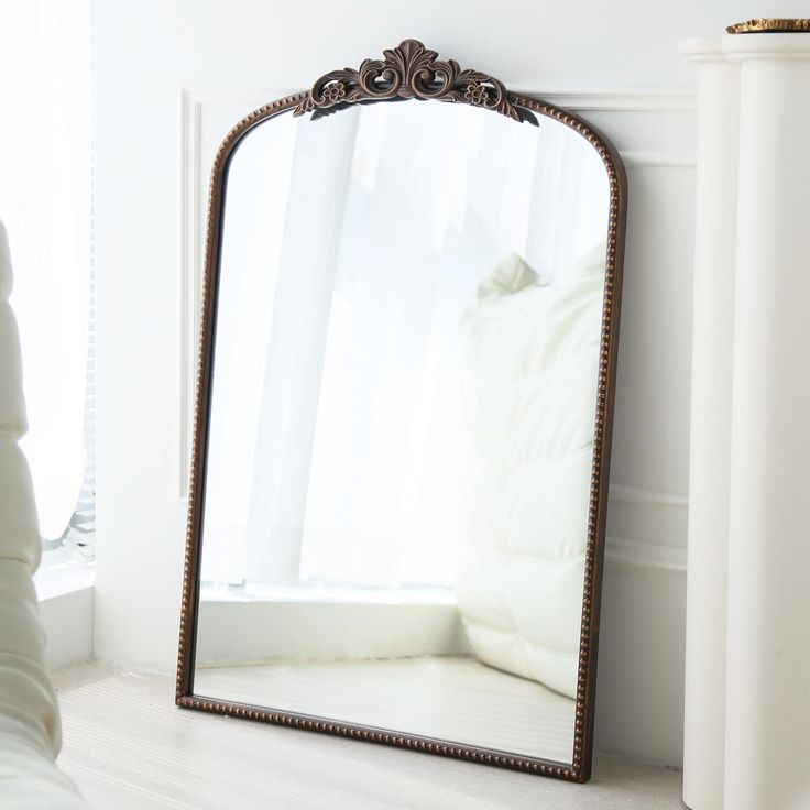 a large mirror sitting on top of a white floor next to a vase and window