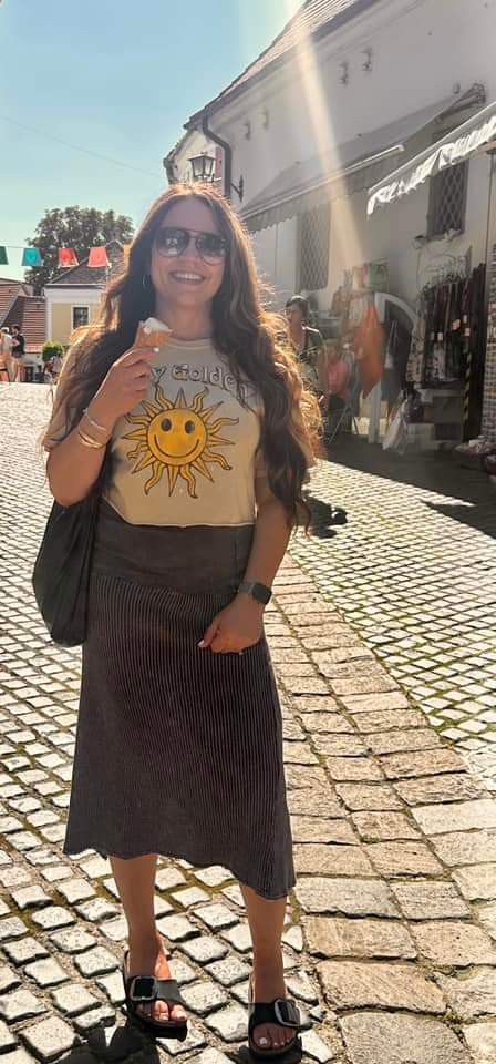 a woman is standing on the street with her hands in her pockets and smiling at the camera