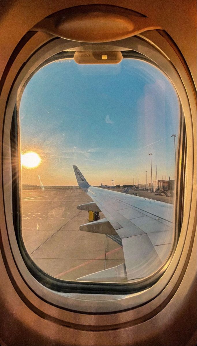 the view from inside an airplane window looking out at the wing and sun in the sky