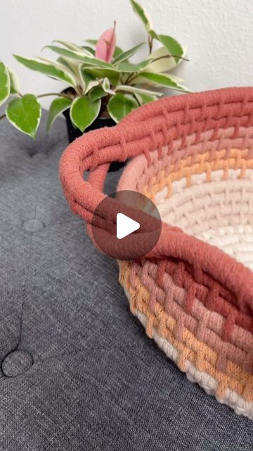 a woven basket sitting on top of a table next to a potted plant