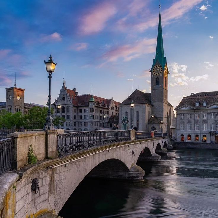 a bridge that has a clock tower in the background and some buildings on both sides