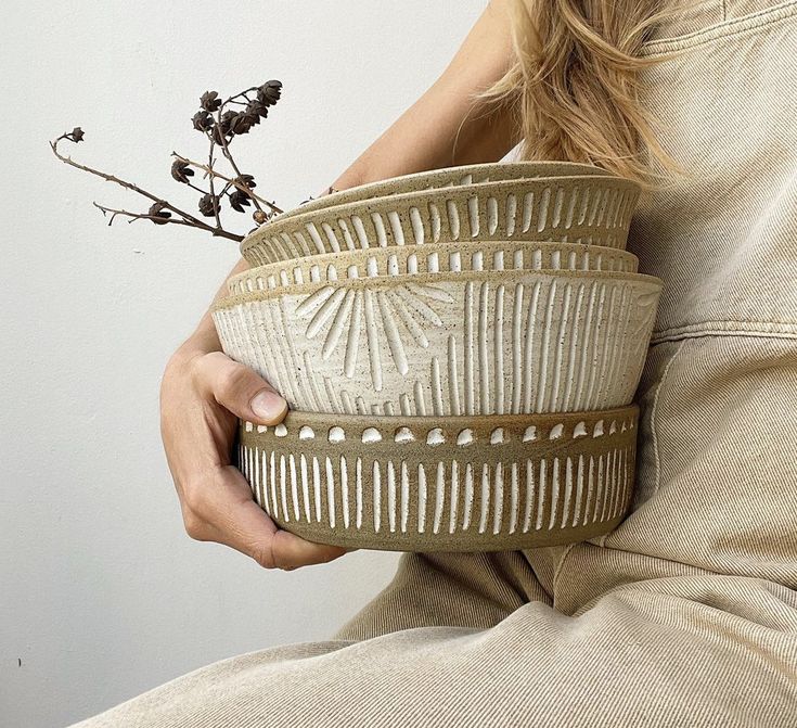 a woman holding a bowl with flowers in it