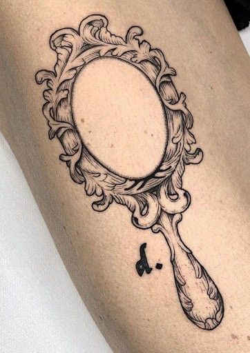 a woman's thigh with a mirror tattoo on it