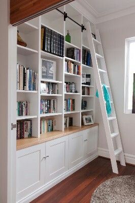 a ladder is hanging from the ceiling in front of a bookshelf with many books on it