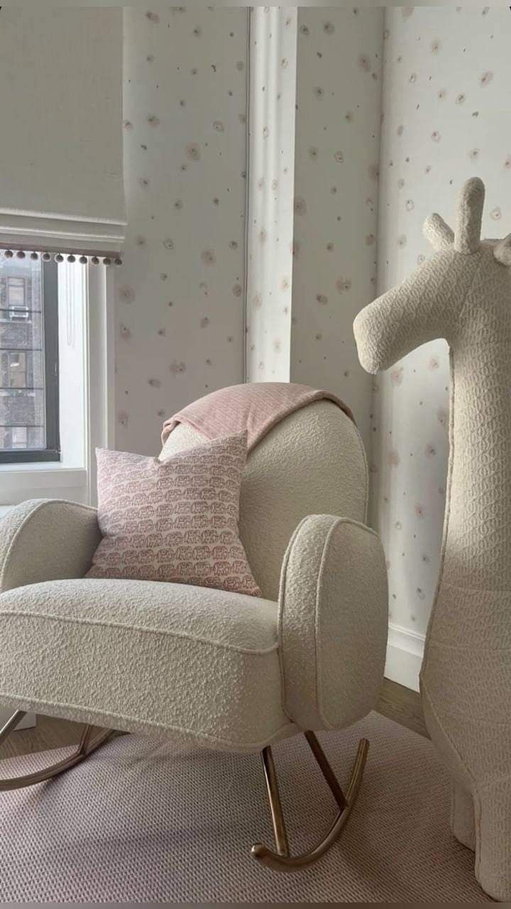 a rocking chair with a giraffe shaped pillow on it's back in front of a window