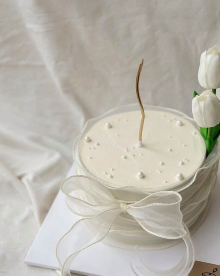 a white cake sitting on top of a piece of paper with a flower sticking out of it