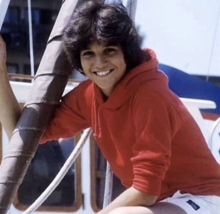 a woman sitting on the side of a boat smiling