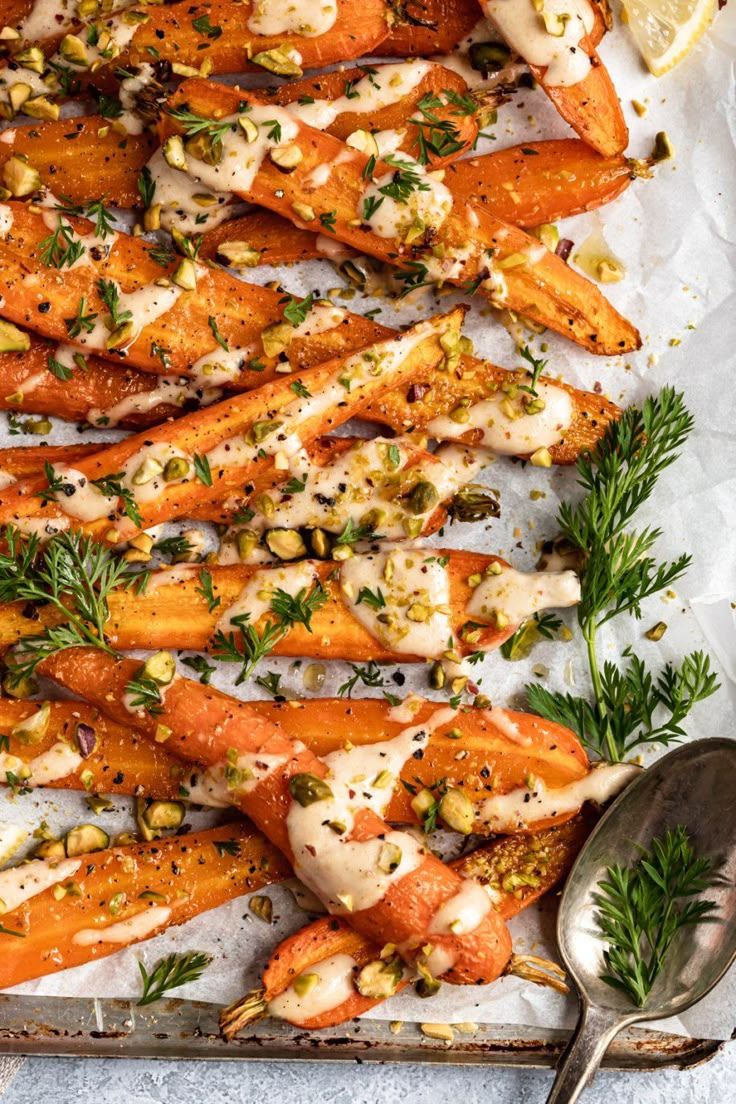 roasted carrots with garlic and herbs on a baking sheet next to a serving spoon