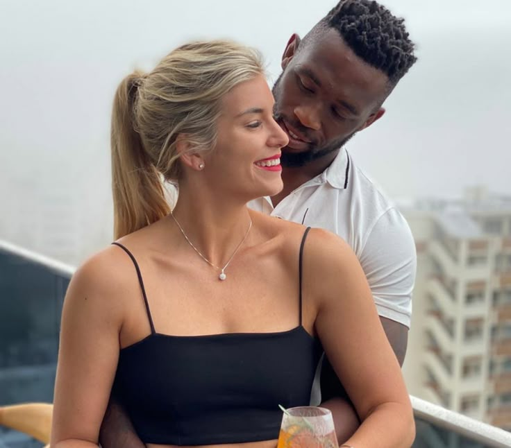 a man and woman standing next to each other on a balcony looking at each other