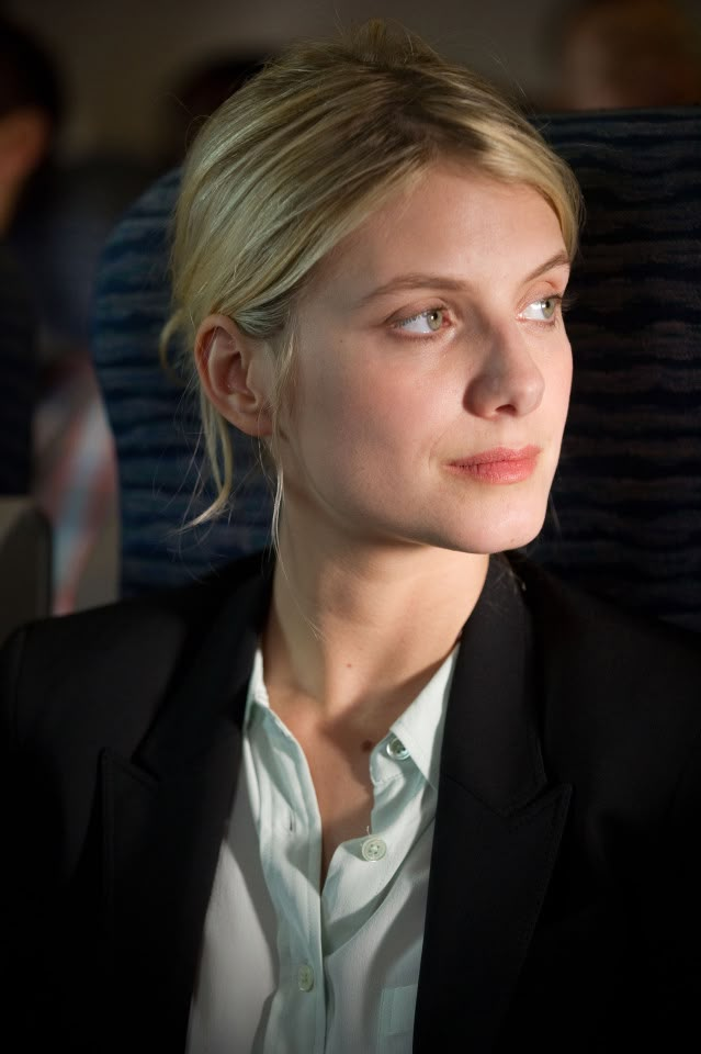 a woman sitting in an airplane looking off into the distance with her eyes wide open