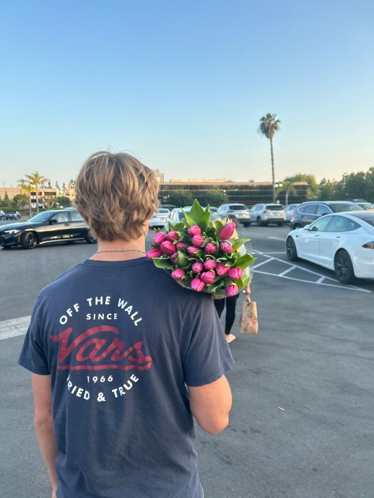 a man in a parking lot with flowers on his shoulder and the back of his head