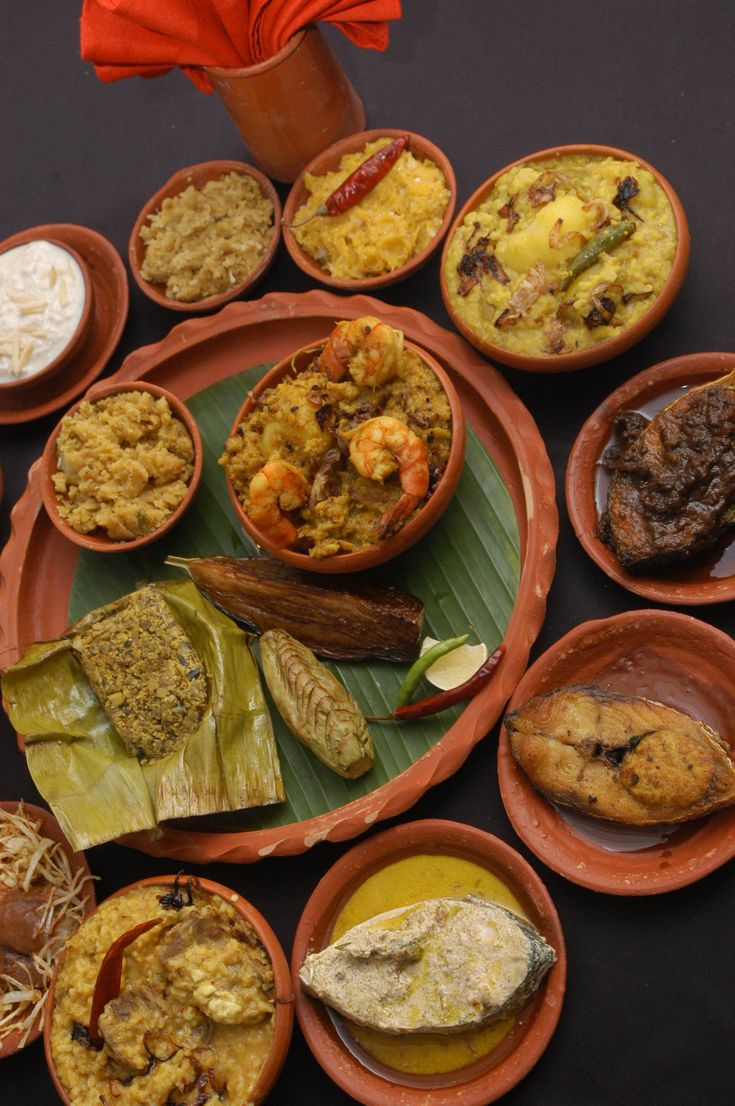 a table topped with lots of different types of food on top of orange plates covered in sauces