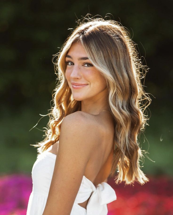 a beautiful young woman with long blonde hair wearing a white dress and smiling at the camera