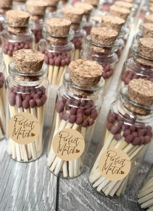 small glass jars filled with matchesticks and labels on top of wooden tablecloth