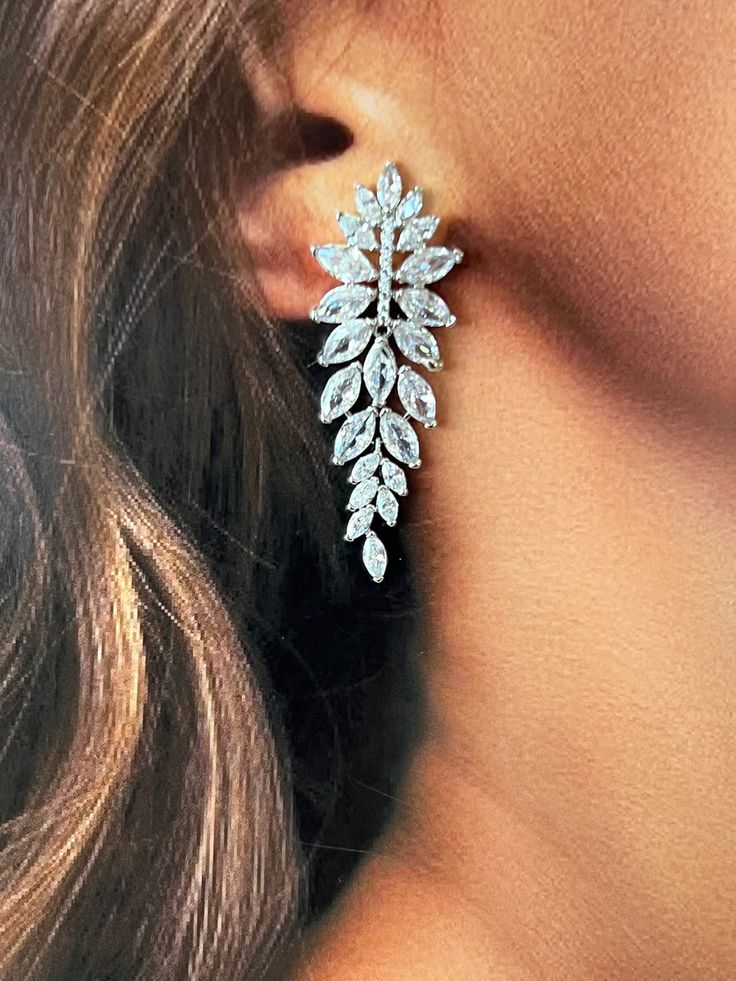 a close up of a woman's face wearing earrings with leaves on them,