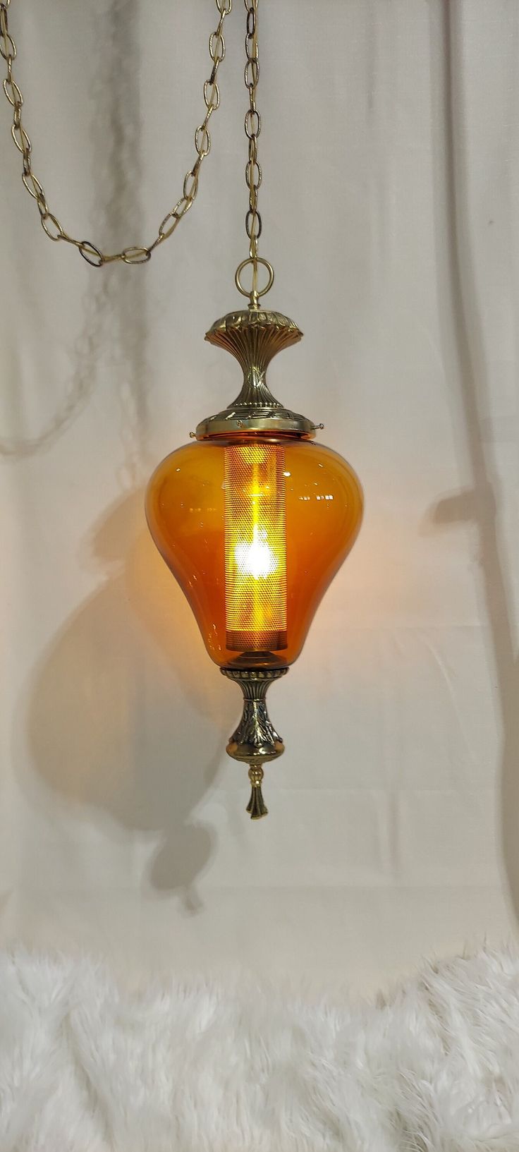 an orange glass light hanging from a chain