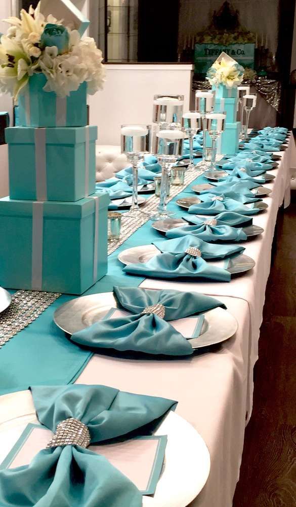 the table is set with blue and white napkins, silverware, and gift boxes