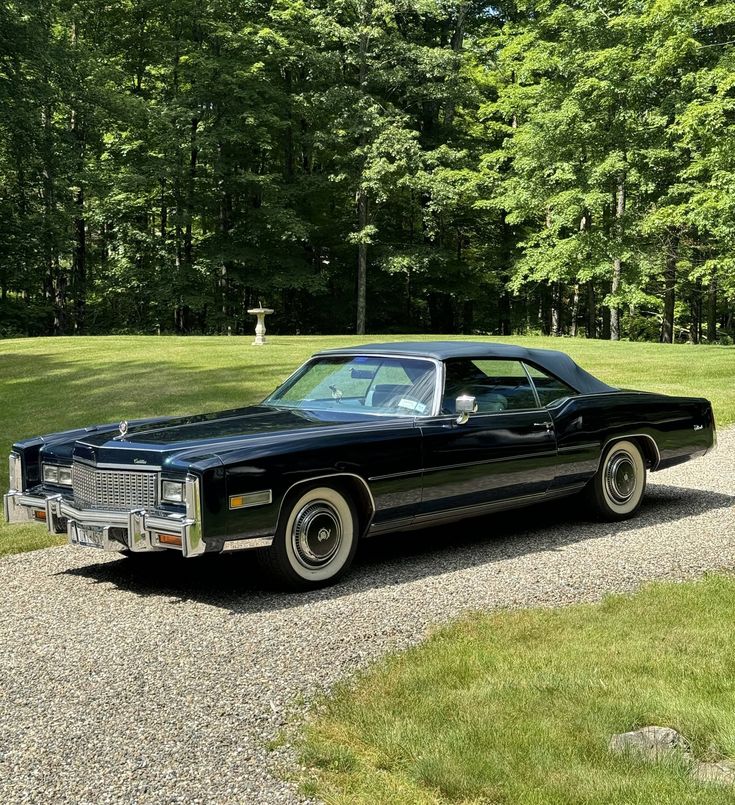 an old black car parked on a gravel road